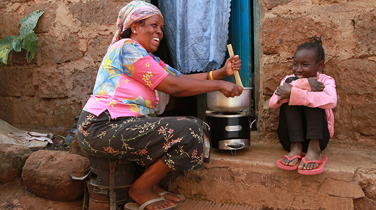 Woman cooking on a cleaner burning cookstove (photo)