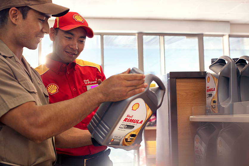Shell Retail employee assists customer in selecting Shell Rimula truck and heavy duty engine oil (photo)