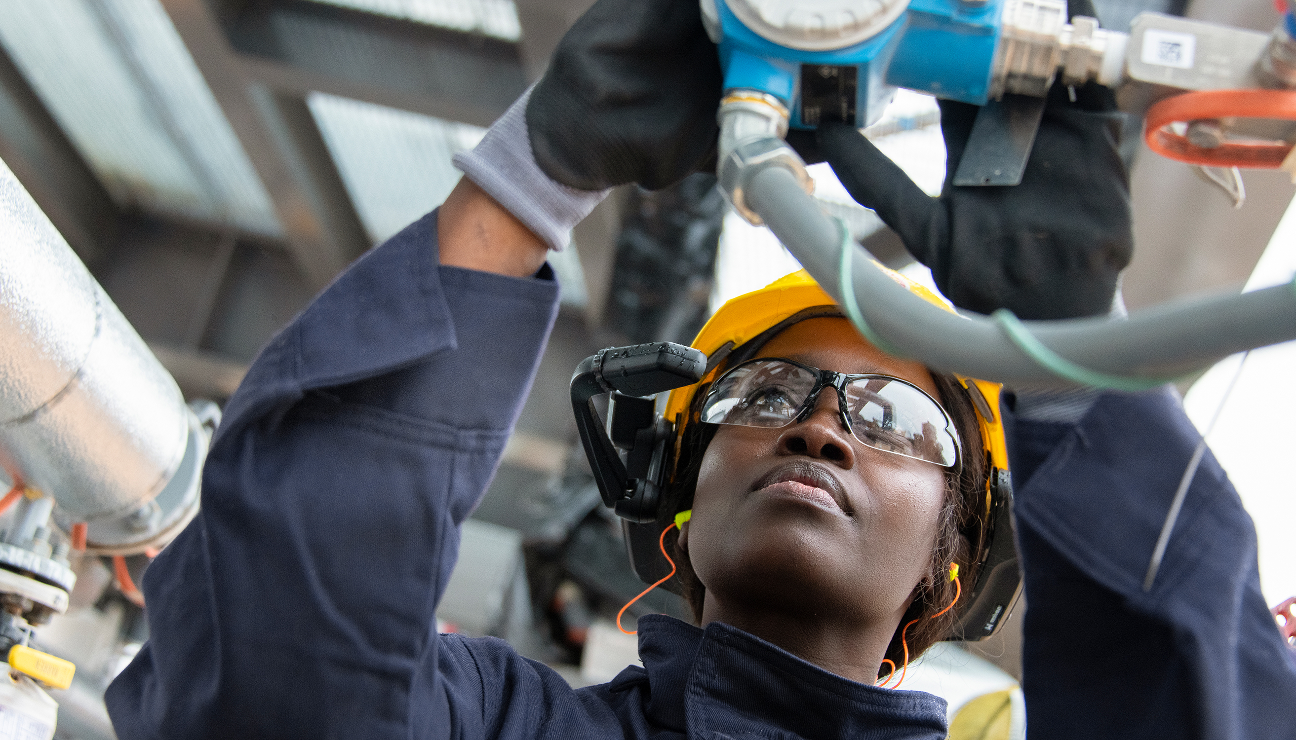 A female operator communicates with an office based team through a microphone, a camera, and a small screen on the lens, the field of the future, a wellpad in the iShale® Program, Permian Basin (photo)