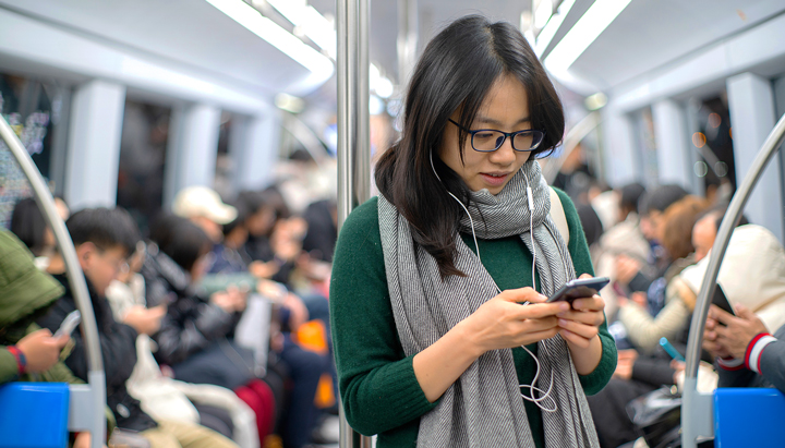 Young woman using her mobile phone on the train, China, 2019 (photo)