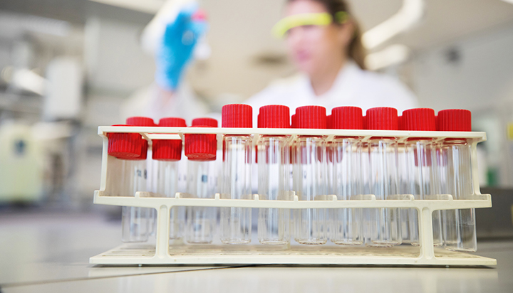 Test tubes, with a woman in the background, at the Qatar Shell Research and Technology Centre. (photo)