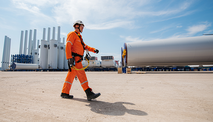 A man walking in front of several wind turbine towers being prepared for dispatch at the Blauwwind consortium site in the Netherlands. (photo)