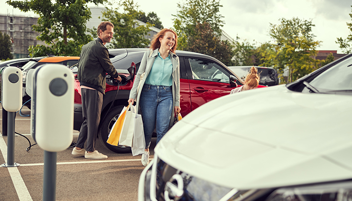 A man and a woman walking among electric cars recharging in a parking lot. (photo)