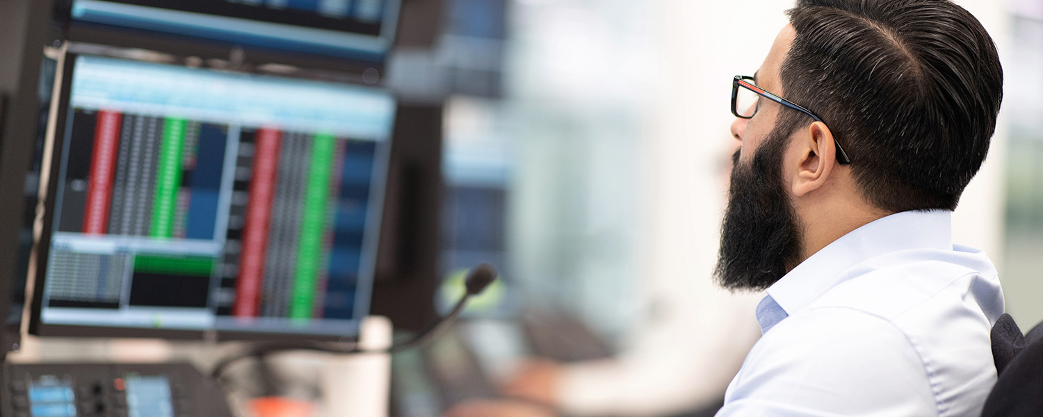 A trader looking at data on screens in London, UK. (photo)