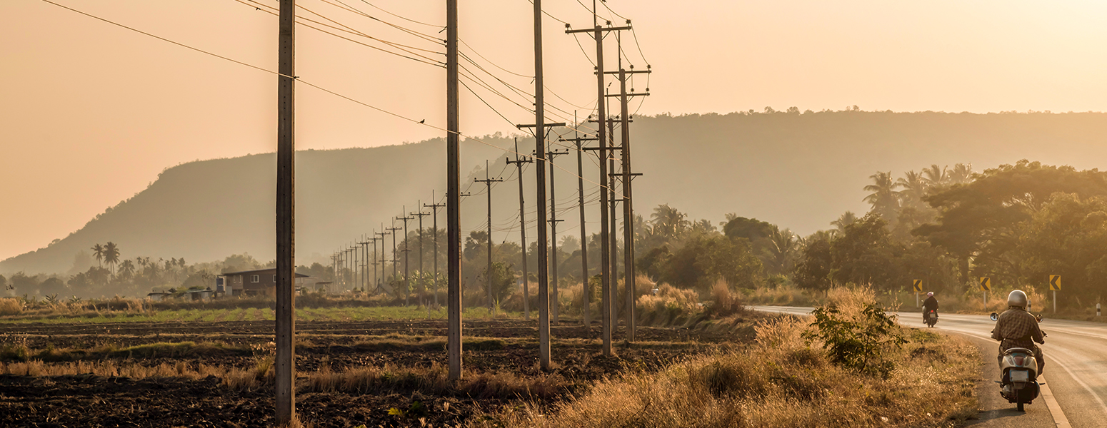 View of electricity pylons near a road with two people on motorcycles (photo)