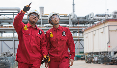 Man and woman walking through a refinery and pointing at something (photo)