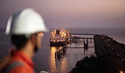 Men with helmet looking at an LNG ship at Hazira, India at night (photo)