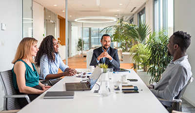 Two men and two women in a meeting room discussing (photo)