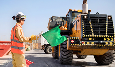 Man using flags to direct a large vehicle (photo)
