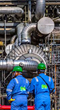 Three men in blue workwear standing in front of the NLNG plant in Bonny, Port Harcourt, Nigeria (photo)