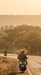 View of electricity pylons near a road with two people on motorcycles (photo)
