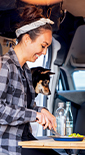 Woman, man and dog sitting in a van and having lunch (photo)