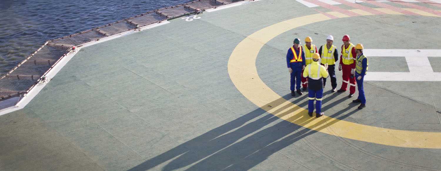 group of men wearing PPE having a Safety briefing on a helipad (photo)
