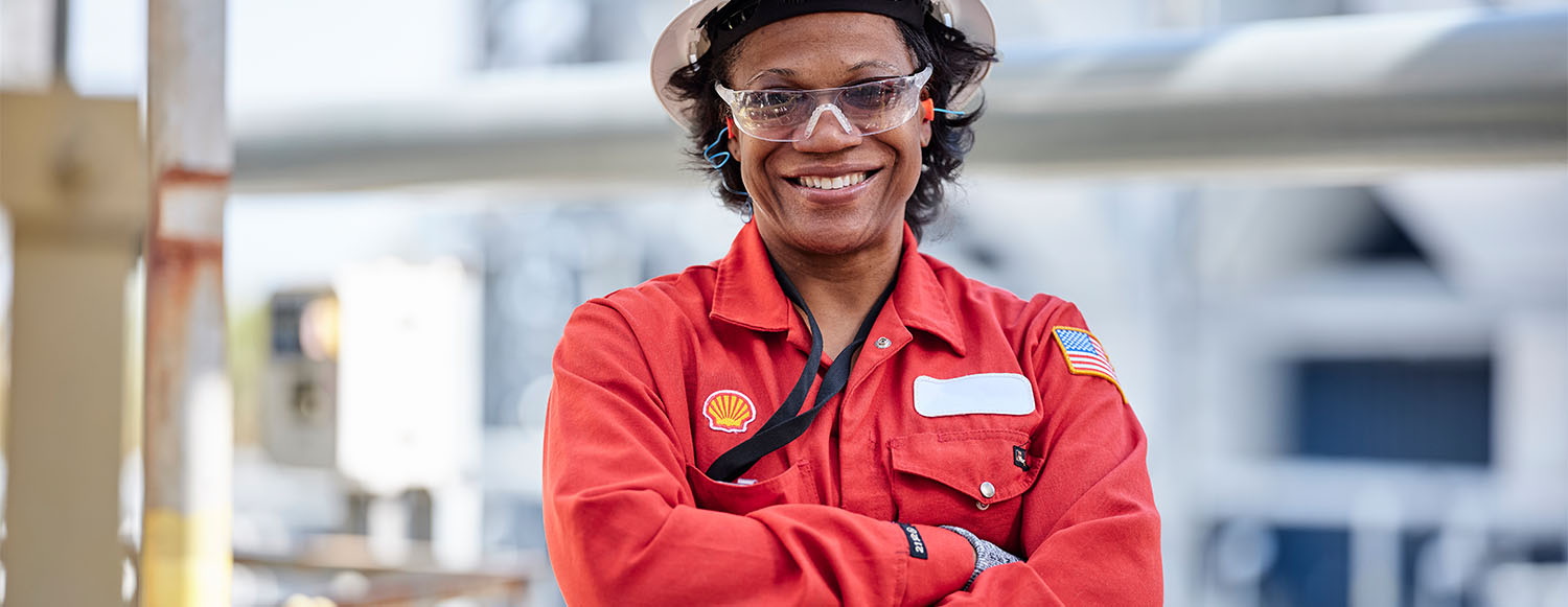 Smiling Shell employee in PPE with her arms crossed at Shell facility in USA (photo)