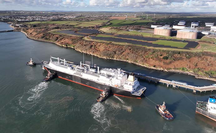 aerial photo of Shell LNG vessel next to pipeline and shoreline with tug boats around (photo)