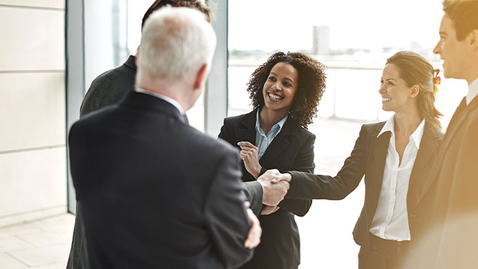 Cropped shot of two businesspeople shaking hands while their colleagues look on in a glass office (photo)