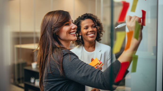 Business women working together to inspire creativity, with adhesive notes on a glass wall in the office.
(photo)