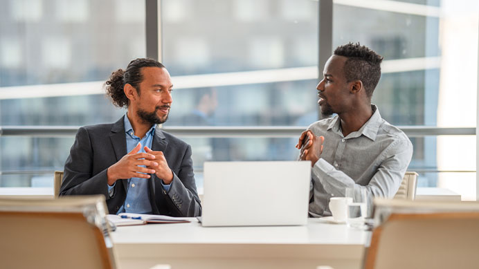 Business discussion between two business working in an office, using a laptop (photo)